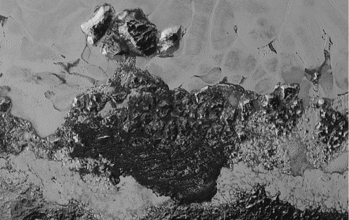 The dunes of Pluto? This image, representing a portion of Pluto's surface some 350 km (220 mi) across, shows some of the planet's older, chaotic terrain at the bottom, and an enigmatic field of dark, aligned ridges that resemble dunes which have caused planetary scientists to feel their eyebrows further vanishing under hair lines. The image was captured from a distance of 80,000 km (50,000 mi) from Pluto.