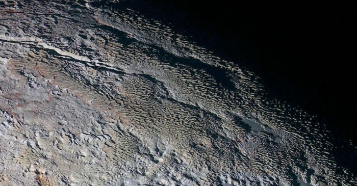 An extended colour image of the Tartarus Dorsa region of Pluto, showing rounded and bizarrely textured mountains which appear covered by intricate but puzzling patterns of blue-gray ridges with reddish material in between. This image is approximately This view, roughly 500 km (312 mi) resolves details and colors on scales as small as 1.3 km (0.8 mi) across (image: NASA/JHUAPL/SWRI)