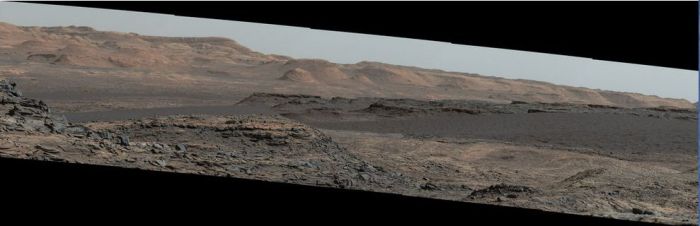 A mosaic of images taken on September 25th, 2015 (Sol 1,115) captures by the right lens of the rover's Mastcam system. .The view is toward south-south-west and reveals the "Bagnold Dunes" as a dark band across the middle of the image, blending with mesas beyond them