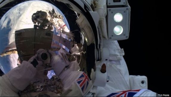 A selfie by Major Tim during his EVA, the camera visible in the reflection in his helmet visor