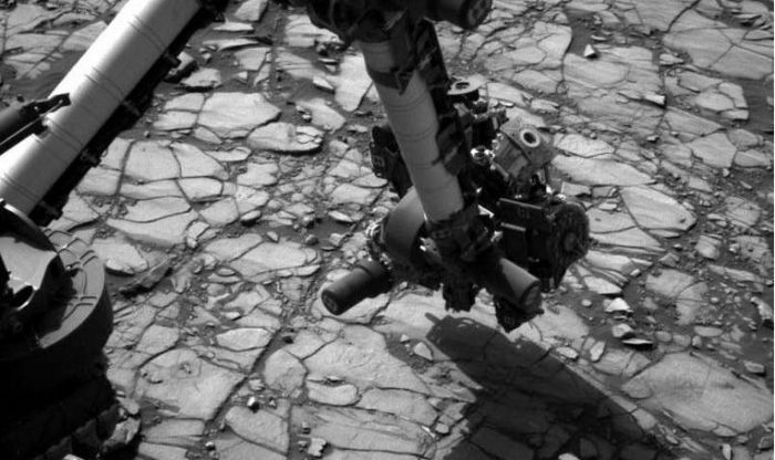 August 2nd, 2016 (Sol 1,418)T: the Navigation Camera (Navcam) on Curiosity's mast images the rover's extended robot arm over a section of the "Marimba" target rock, ready to use the wire brush mounted on the "hand" at the end of the arm in order to scour surface material which otherwise might contaminate and samples gathered from the rock, prior to the rover taking a drilling sample. Credit: NASA/JPL / MSSS