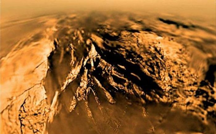 Titan as seen by Huygens from an altitude of 7 km (4.4 mi) on January 14th, 2005, with the probe still some 20 minutes from touchdown. The curvature evident in the image is an artefact of the image system and distortion due to the atmosphere. Credit: ESA